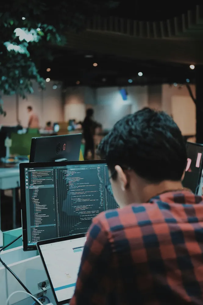 A developer writing code at a desk in an open office